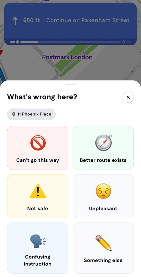 The "What's wrong here?" sheet opened over a dimmed turn-by-turn ride, with a location chip reading 11 Phoenix Place and six report options: Can't go this way, Better route exists, Not safe, Unpleasant, Confusing instruction, Something else.